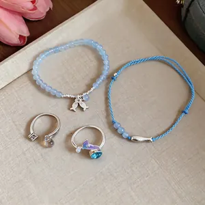 Detailed view of fresh summer blue beaded fish bracelet and woven rope jewelry set on tray