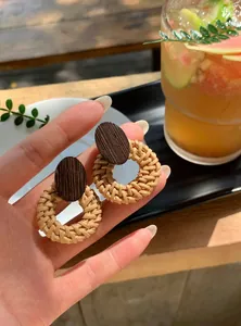 Dettaglio di orecchini a cerchio in rattan fatti a mano con parte superiore in legno.