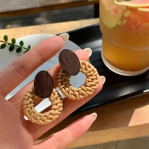 Dettaglio di orecchini a cerchio in rattan fatti a mano con decoro in legno scuro