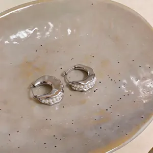 French style geometric silver hoop earrings with pearl bead inlay on a ceramic plate