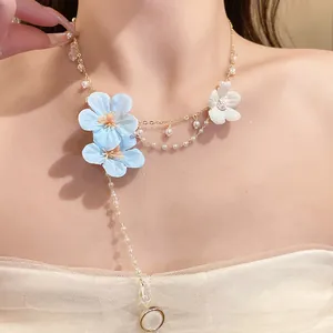 Close-up view of a sweet blue fabric flower necklace with pearl beads and tassel detail.