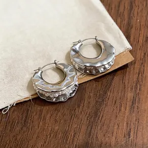 Elegant French-style silver hoop earrings with white seed pearls on a linen background