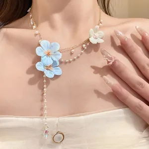 Detail shot of a sweet blue fabric flower necklace with elegant pearl bead tassels