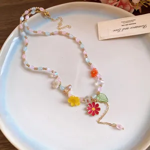 Detail van een kleurrijke kralenketting met pastelkleurige bloemhangers op een bord