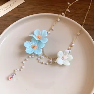Macro detail of the fabric flowers and pearl beadwork on this elegant floral tassel necklace