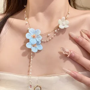 Close-up detail of the elegant blue and white fabric flower necklace with pearl bead tassels.