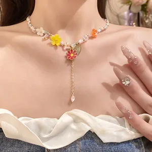 Detailopname van stenen kralenketting met kleurrijke hangers van harsbloemen op model.