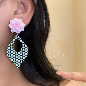 Pink resin flower stud earrings with green polka dot diamond pendant shown on model