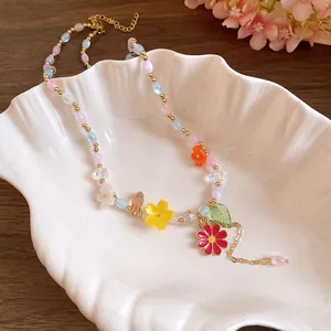 Detail van kleurrijke kralenketting met harsbloemen in een schelpvormige schaal