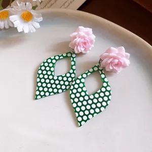 Elegant pink resin flower earrings with green polka dot diamond drops shown in detail.