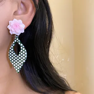 Detailed shot of elegant resin pink flower earrings with green polka dot pendants