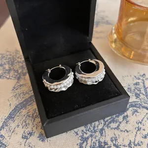 Close-up of silver geometric hoop earrings with pearl bead inlay in black jewelry box