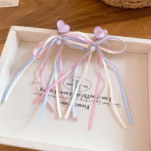 Detail of French resin heart earrings with colorful ribbon bows and pearls