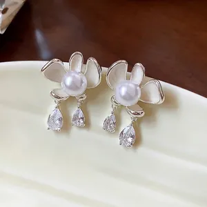Elegant silver flower stud earrings with pearls and teardrop crystals on ceramic plate