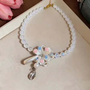 Iridescent beaded necklace with floral tassel and pearl drops on a display tray