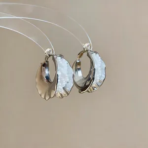 Close-up of elegant irregular silver hoop earrings with white clustered pearl beads