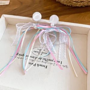 Close-up of French style resin pearl earrings with delicate lace and multi-color ribbon bows