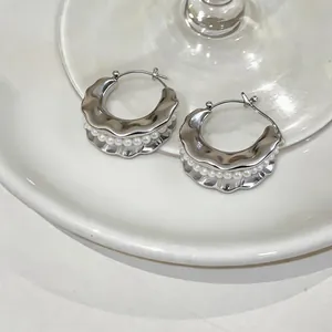 Macro view of French style silver wavy hoop earrings with integrated white pearl beads