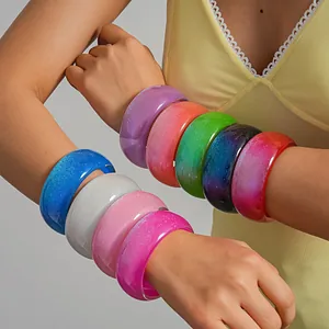 Detailed macro view of colorful glitter resin geometric bangles on model's arms