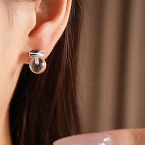 Detailed close-up view of a minimalist clear resin round stud earring worn on a model's ear