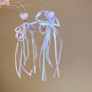 Detail of French style earrings with resin heart, ribbons, and beaded tassels.