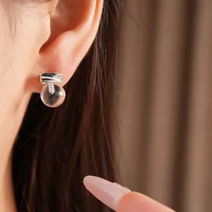 Detailed close-up showing a minimalist clear resin round stud earring worn on the ear