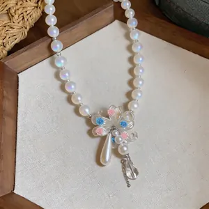 Close-up of iridescent pearl necklace with floral pendant and teardrop tassel detail.