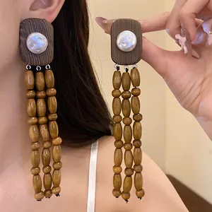 Close-up detail of vintage wood earrings featuring white pearl accents and long bead tassels