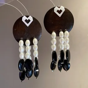 Macro view of vintage tassel earrings with dark wood disc and white pearl strands