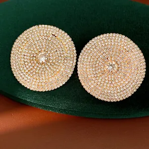 Primer plano de pendientes redondos con brillantes strass y aguja de plata de ley.