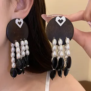 Close-up detail of vintage style tassel earrings with pearls, dark wood and heart studs.