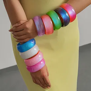 Close-up detail of vibrant colorful glitter resin bangle bracelets stacked on a model's arms