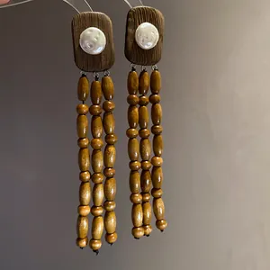 Detailed view of vintage wooden tassel earrings with central pearl accent