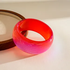 Close-up of vibrant red and pink iridescent chunky resin bangle with glitter finish