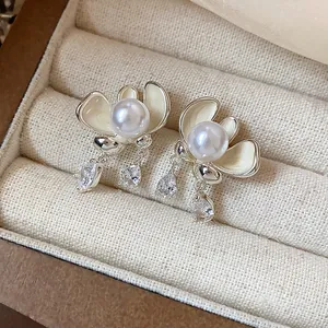 Close-up detail view of elegant silver-needle flower pearl stud earrings with dangling crystals