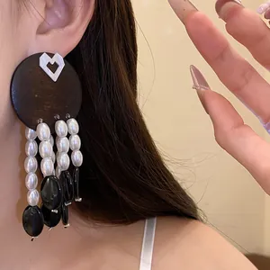 Detailed close-up showing a vintage style earring with wood disk and pearl tassels