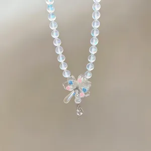 Close-up of iridescent beaded necklace with clear flower and drop pearl pendant