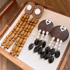 Detailed view of vintage wood and faux pearl tassel earrings displayed on a wooden tray