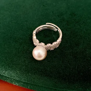 Close-up detail of silver open ring with large pearl and sparkling pavé zircons