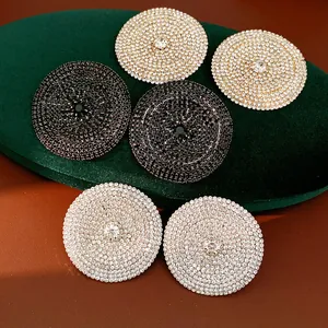 Vista detallada de pendientes de botón redondos geométricos con strass en negro y plata
