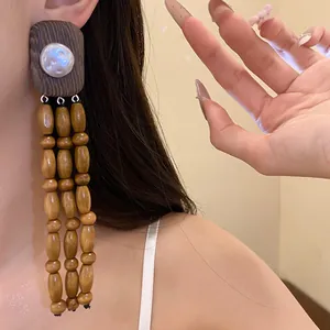 Detailed close-up showing vintage wooden bead tassel earrings with central pearl on model