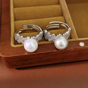 Macro detail of elegant silver-tone open ring with white pearl and micro zircon setting.
