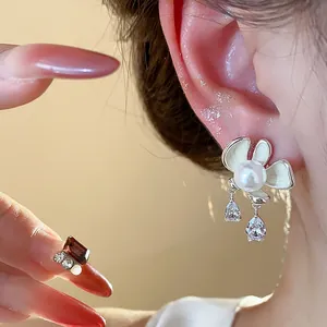 Close-up of elegant Korean style flower pearl earrings with teardrop crystal charms.