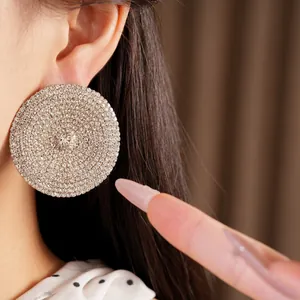 Primer plano de pendientes redondos plateados grandes con cristales brillantes