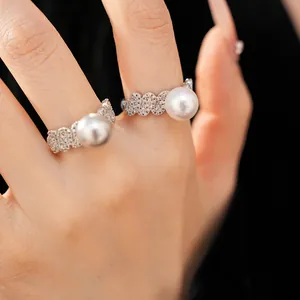 Detailed view of elegant silver scalloped ring set with sparkling zircons and a white pearl.