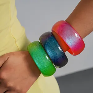 Detailed macro view of vibrant gradient resin bangles with a colorful glittery finish