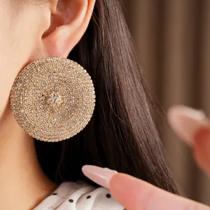 Primer plano de pendientes redondos dorados con brillantes cristales claros de imitación