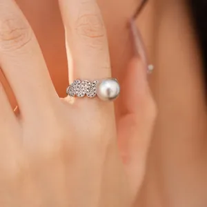 Detailed view of elegant minimalist zircon pavé open ring with grey pearl on finger