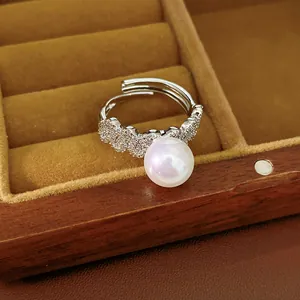 Close-up detail of a silver open ring with a large pearl and sparkling zircon