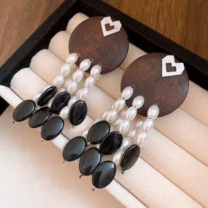 Close-up detail of vintage style wooden earrings featuring elegant pearl and black stone tassels